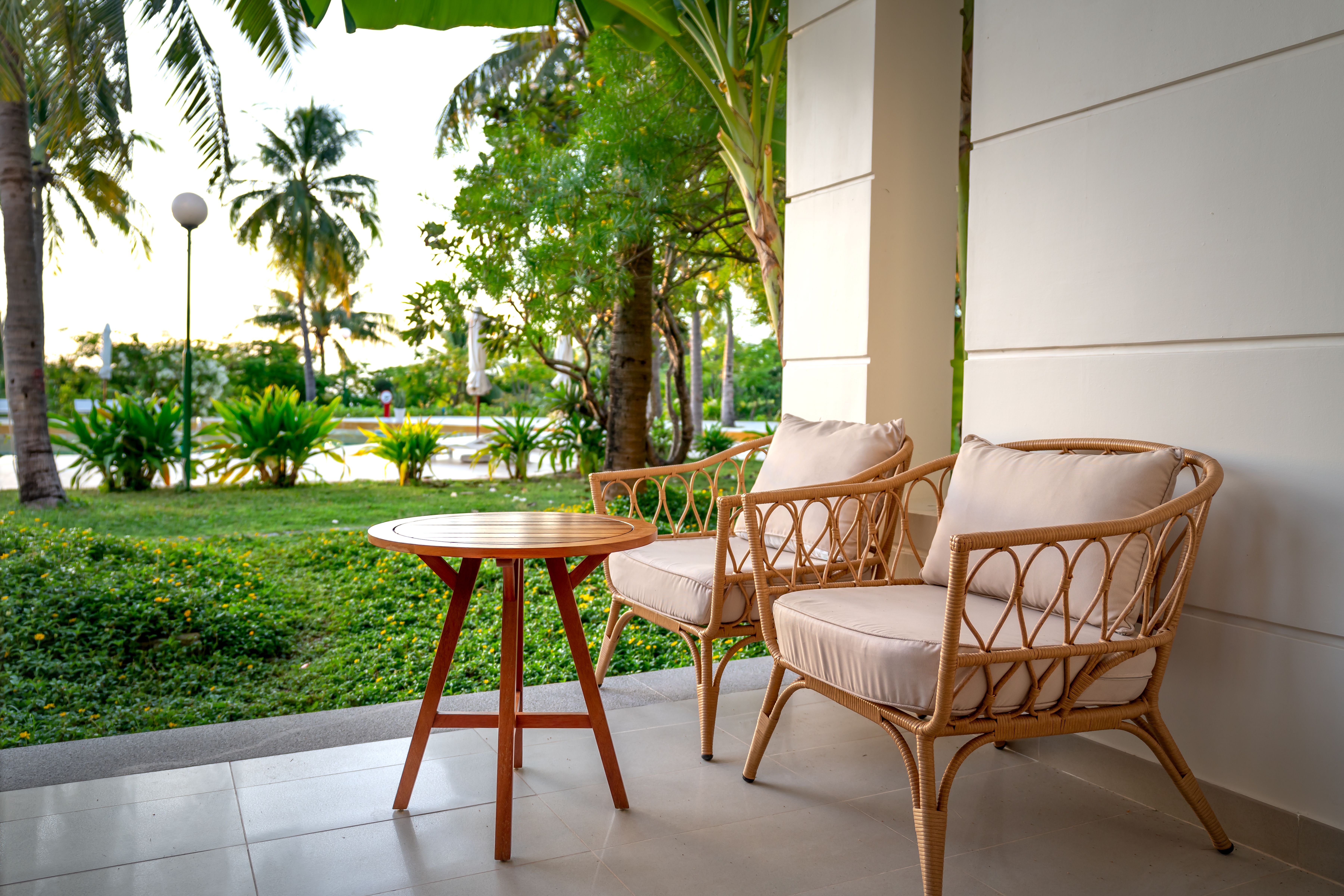 Serene patio with rattan chairs overlooking a lush tropical garden, suitable as a video backdrop.