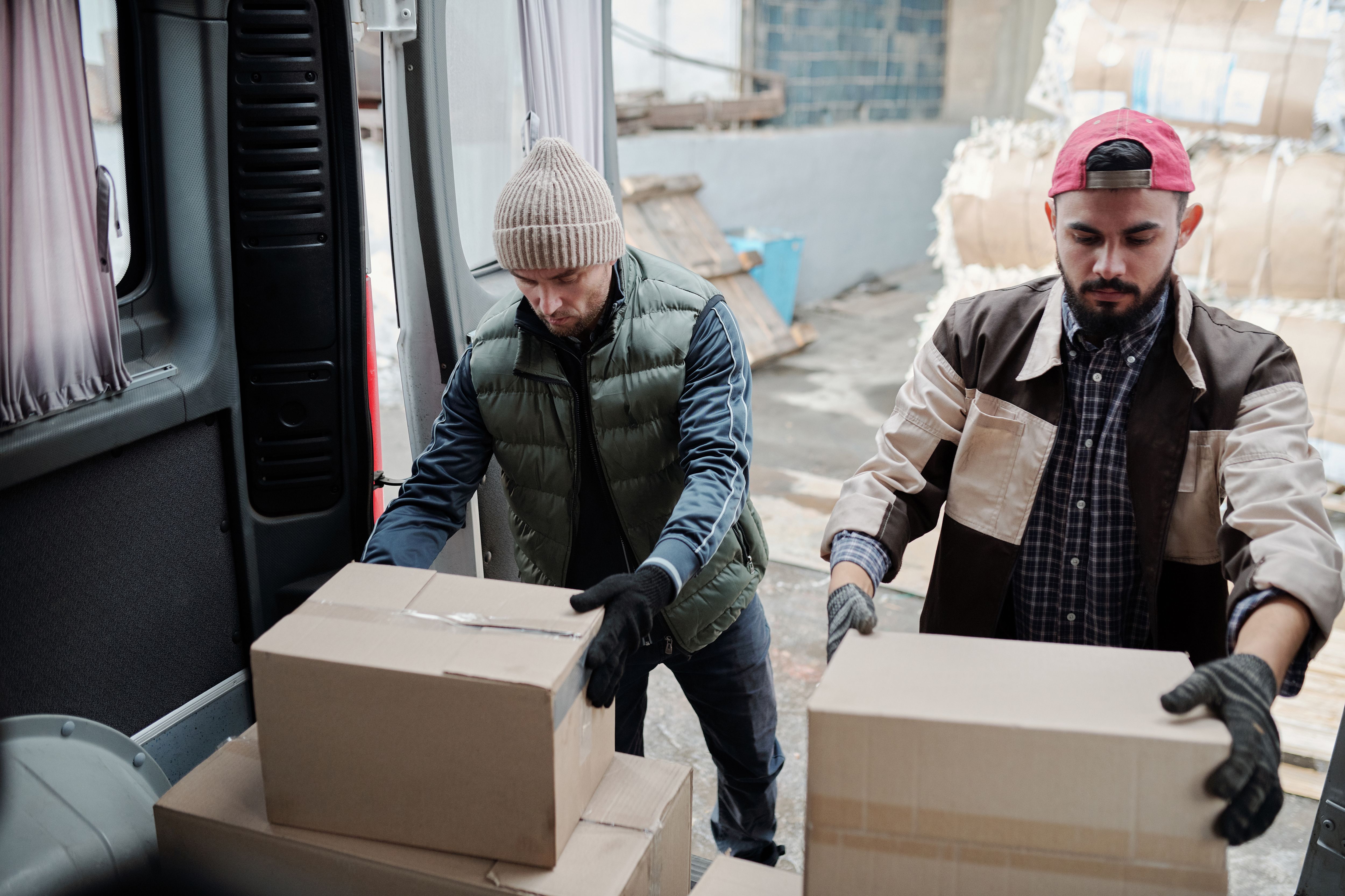 Workers loading packages into a delivery van, showing how higher fuel costs affect business distribution.