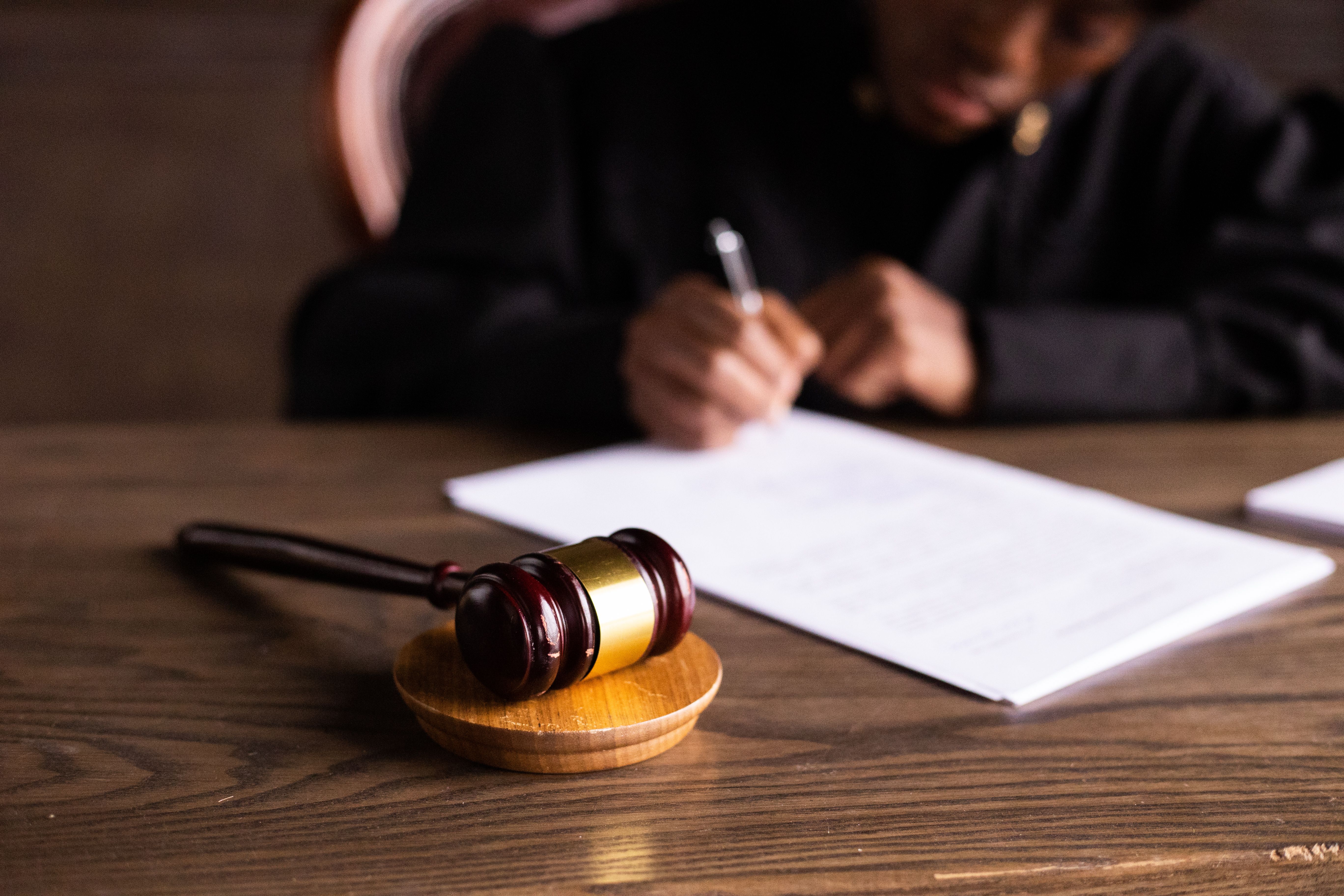 A judge signing documents beside a gavel, representing courtroom decisions in large-scale litigation.