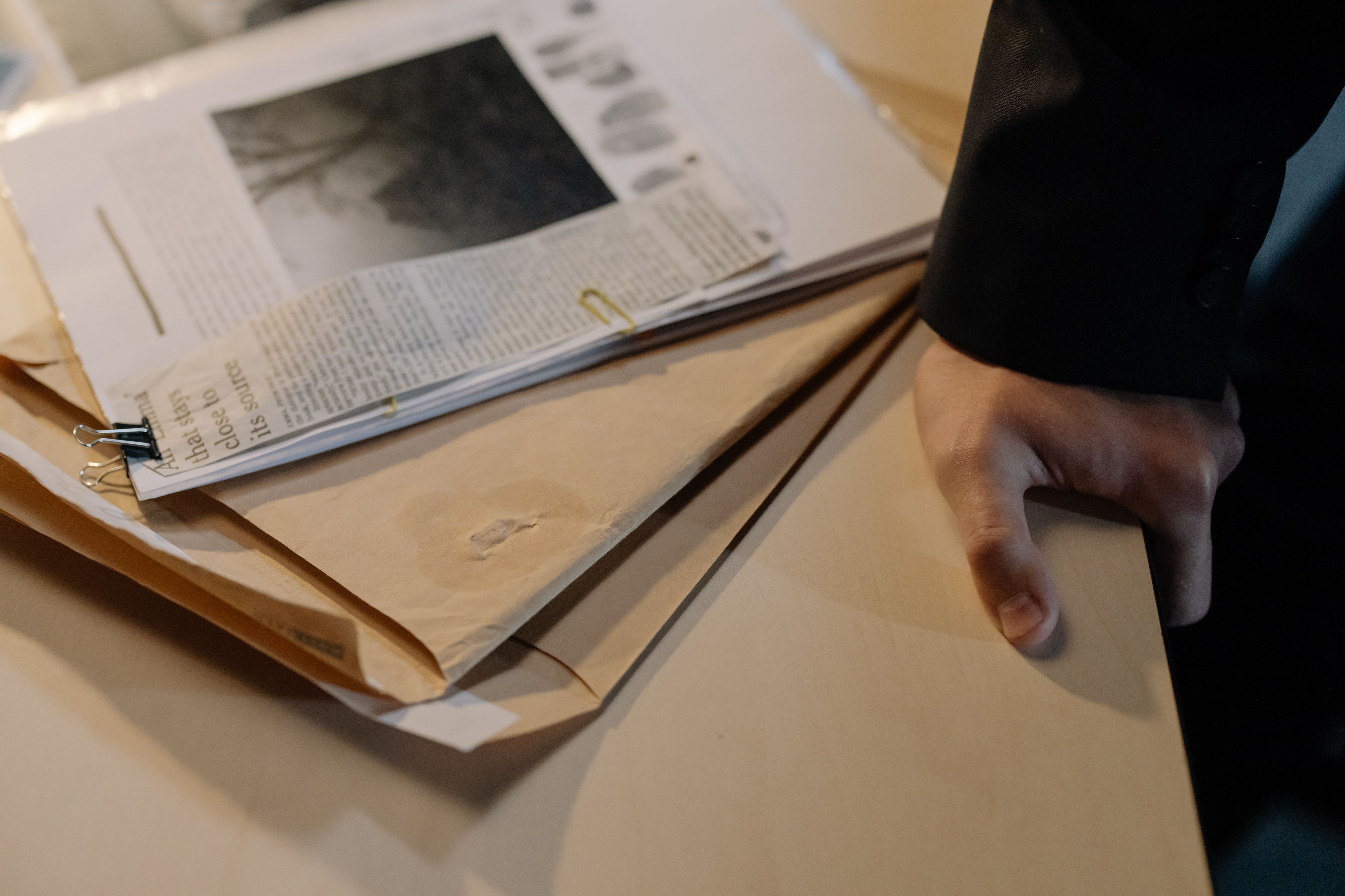 A legal professional reviewing investigative documents and newspaper clippings, representing evidence preparation in a major case.