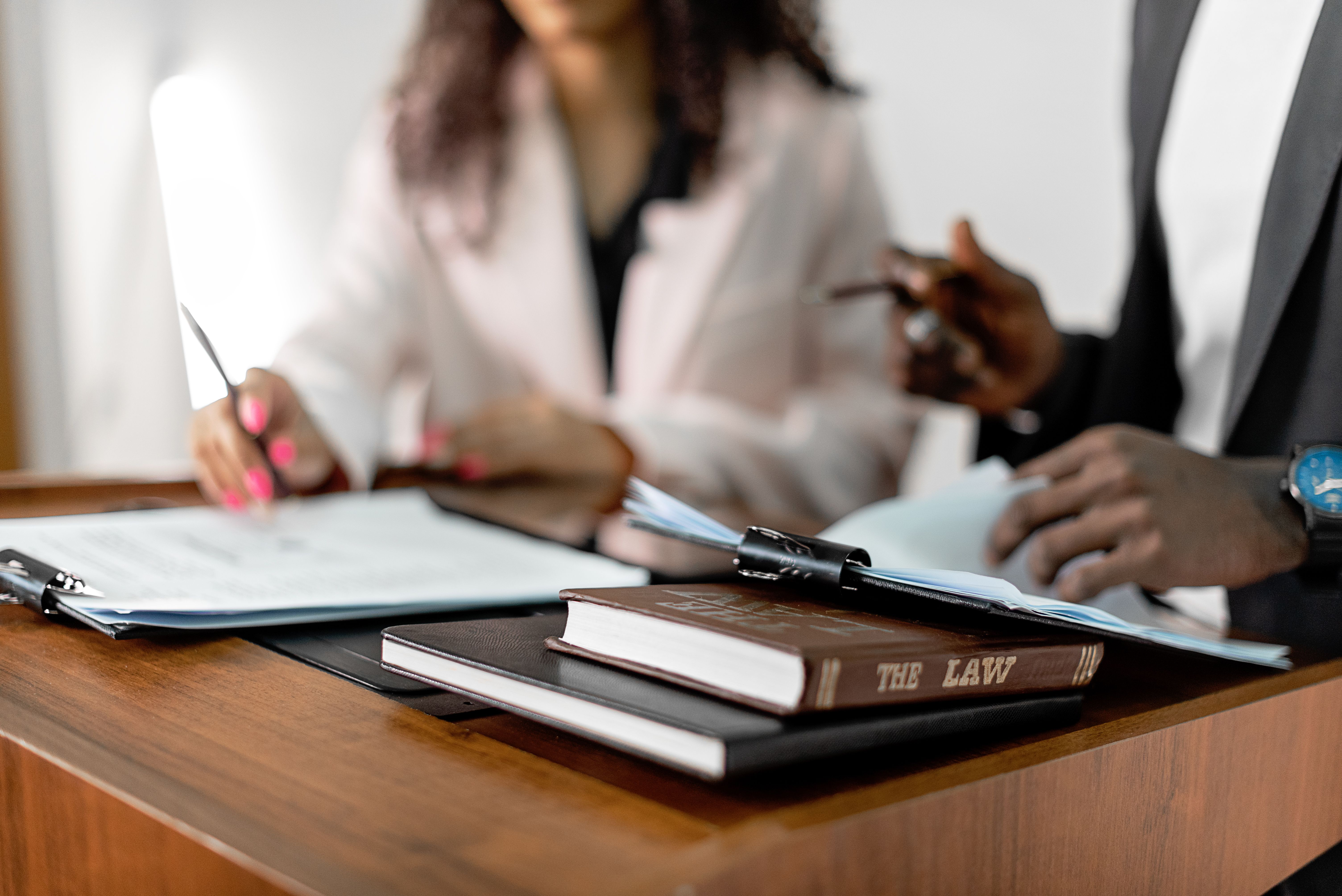 Two lawyers reviewing documents and law books together in a professional legal setting.
