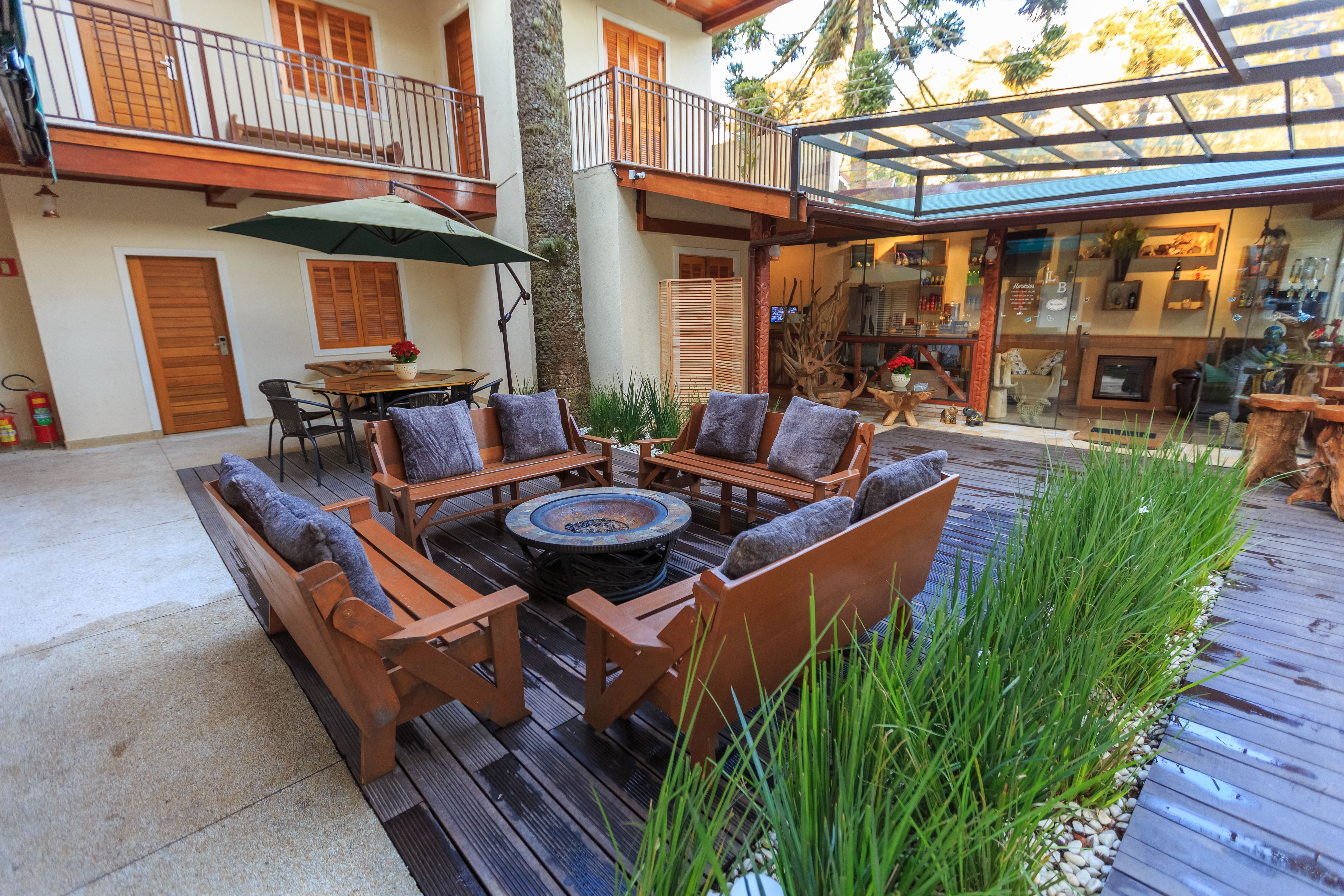 Modern outdoor patio with wooden furniture and abundant plants in a residential courtyard.