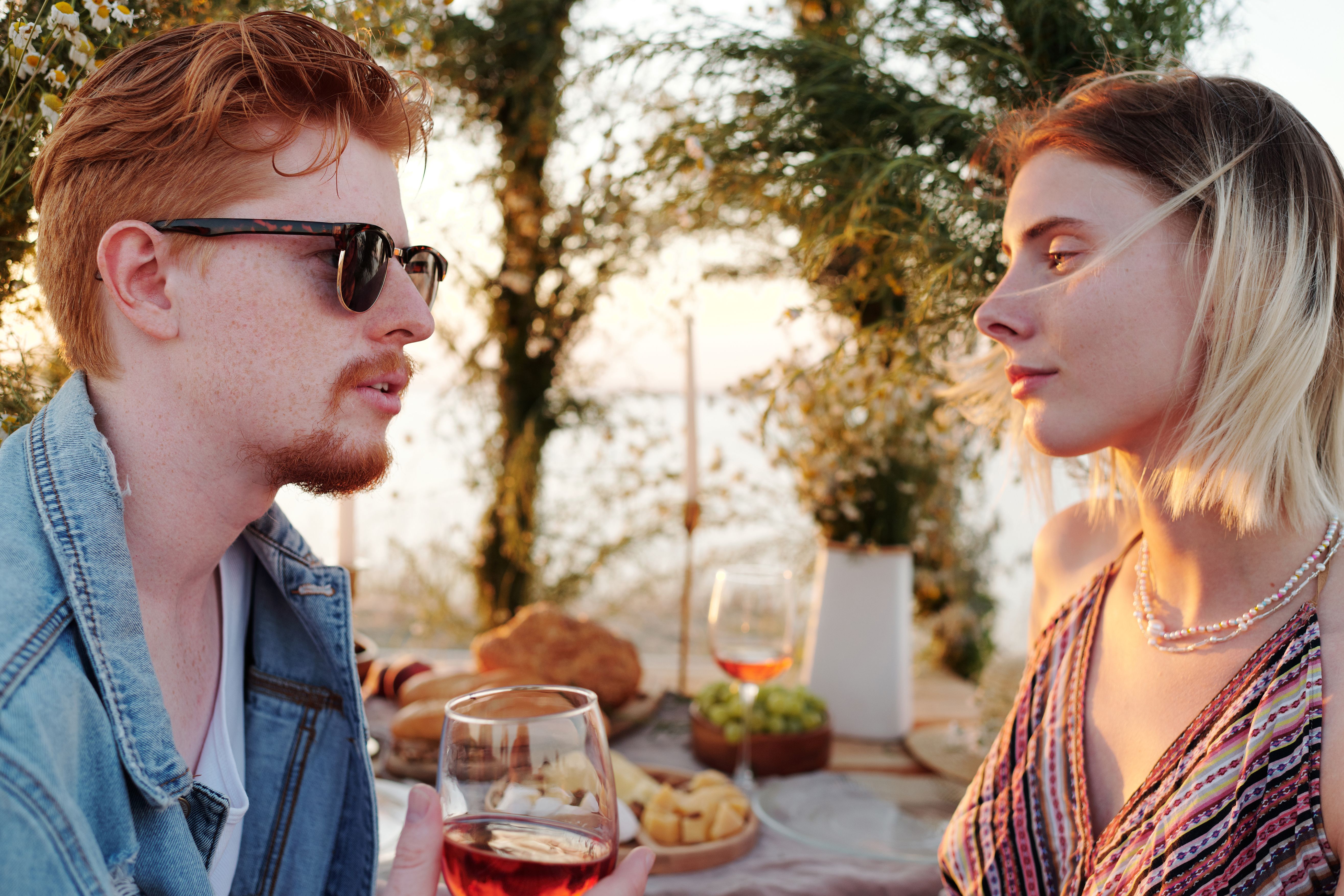 Young couple sharing wine and conversation during a beachside date at sunset